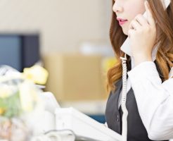 パソコンを使って電話をかける女性